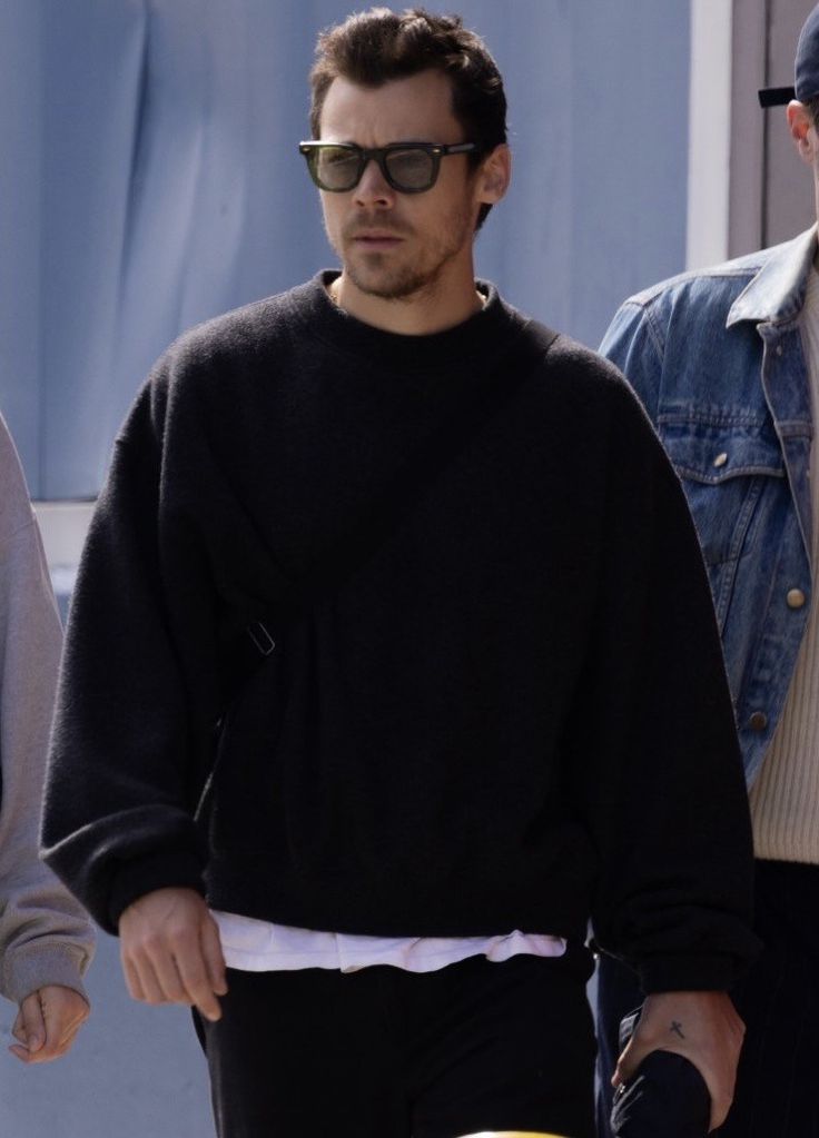 a man in black sweater and sunglasses walking down the street