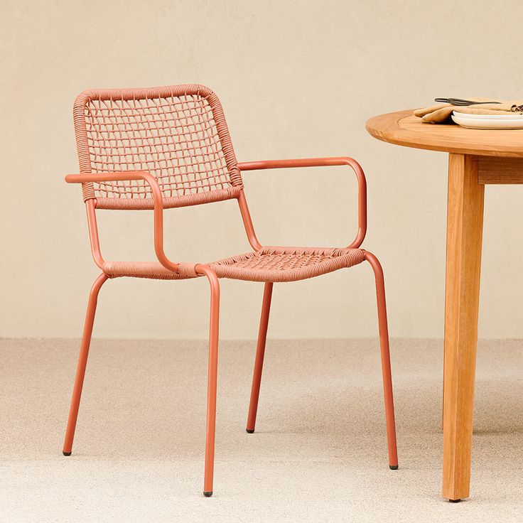 an orange chair sitting next to a table with a plate on it and a fork in the other hand