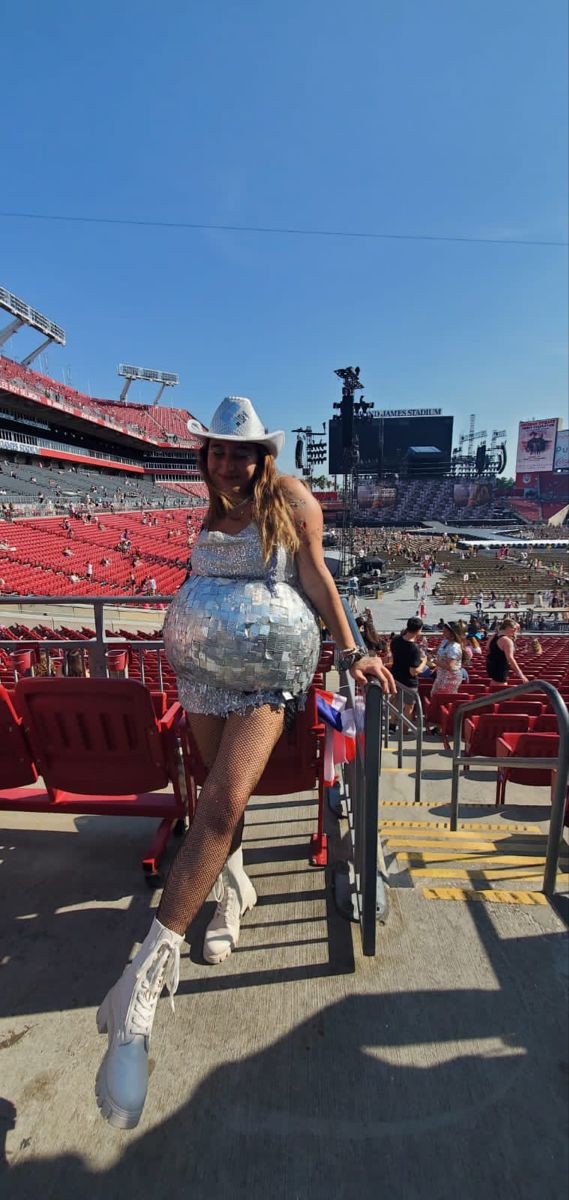 a woman in a disco dress is sitting on a chair at a stadium with her legs spread out