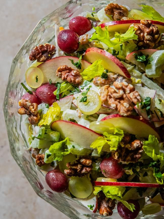 a salad with apples, grapes and walnuts in a glass bowl on a table