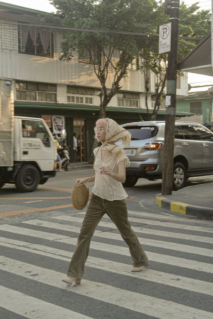 a woman walking across a street holding a basket