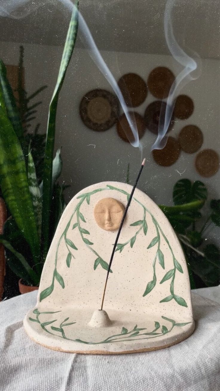 a ceramic incense burner sitting on top of a table next to a potted plant