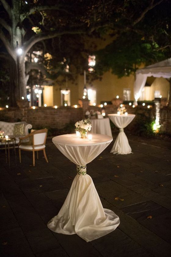 the tables are covered with white tablecloths and decorated with flowers, candles and greenery