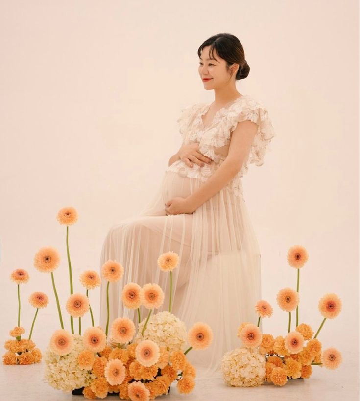 a pregnant woman sitting in front of flowers