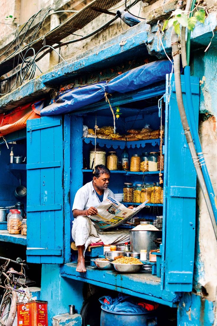 a man sitting on the back of a blue truck with food in front of him