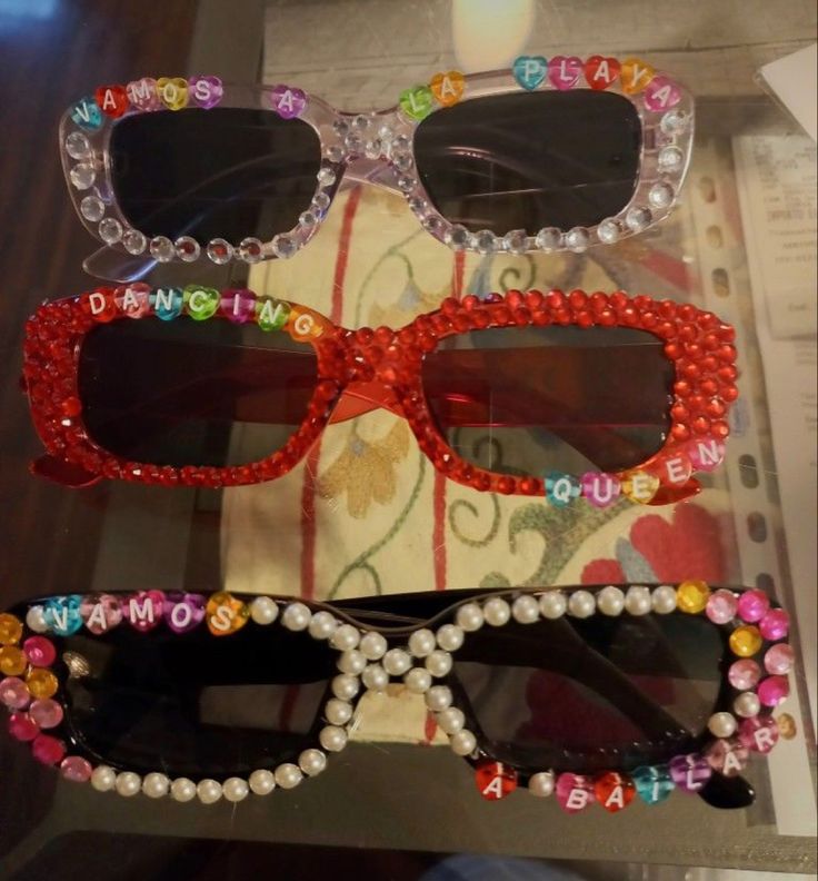 two pairs of sunglasses with beads on them sitting on top of a table next to a candle