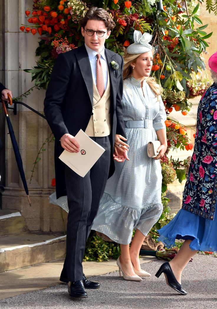 a man and woman dressed in formal attire walking next to each other on the street