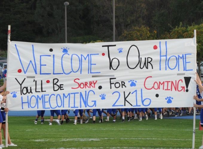 a group of cheerleaders holding a welcome to our home sign on the field