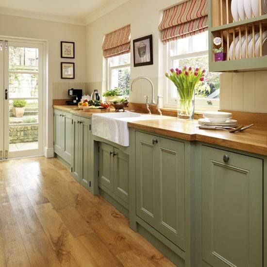 a kitchen filled with lots of green cabinets and counter top space next to a wooden floor