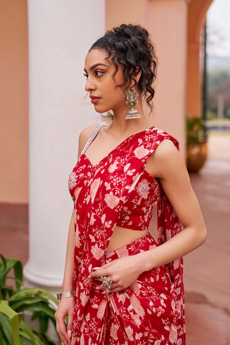 Introducing this glamorous red pre-draped sari ensemble, accompanied by a printed blouse adorned with sequin highlights and delicately embroidered straps. This ensemble combines traditional elegance with modern flair, making it perfect for special occasions where you want to dazzle and shine. Elevate your style with this captivating outfit. Red Draped Georgette Saree, Red Draped Georgette Choli, Party Wear Floral Print Choli With Traditional Drape, Party Choli With Floral Print And Traditional Drape, Red Draped Dupatta Set, Floral Print Sharara With Traditional Drape For Party, Red Draped Sets With Dupatta, Red Draped Set With Dupatta, Festive Floor-length Pre-draped Saree With Floral Print