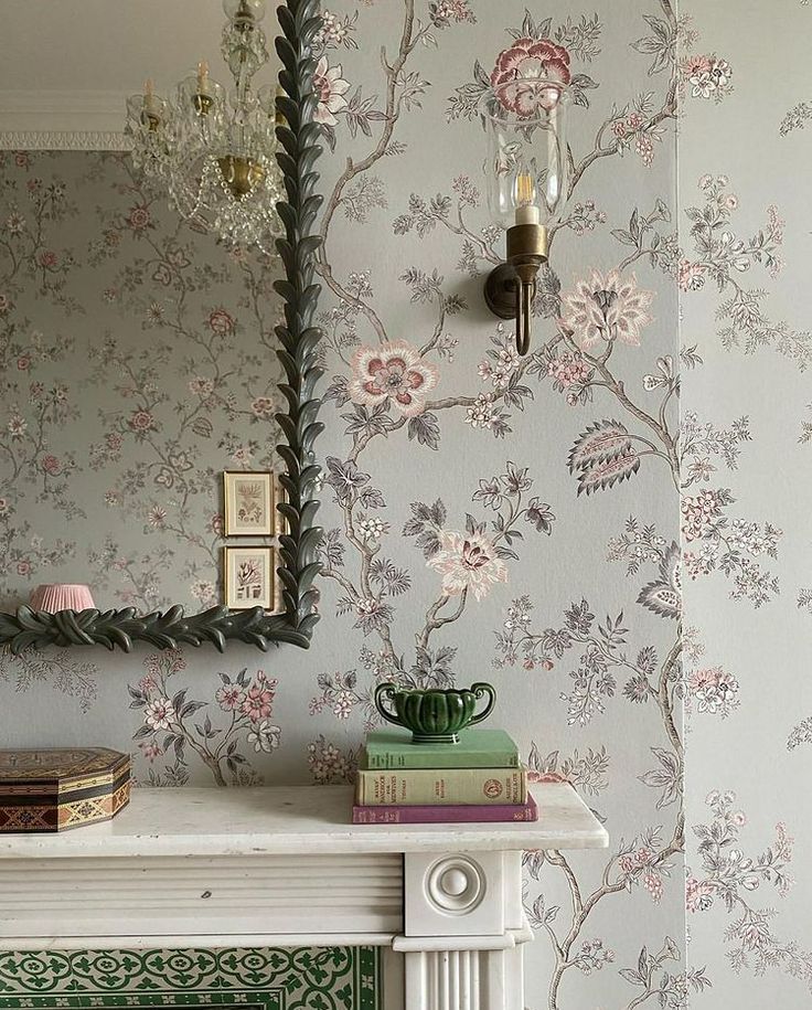 a fireplace with a mirror on top of it next to a wall papered with flowers