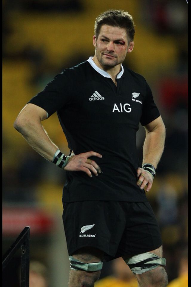 a rugby player standing on the sidelines with his hands on his hips looking at something