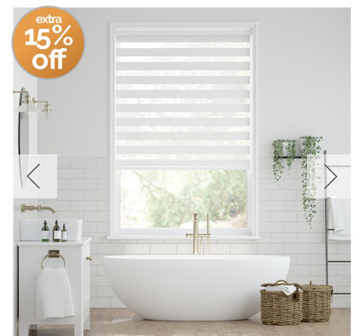 a white bath tub sitting under a window next to a sink and toilet in a bathroom