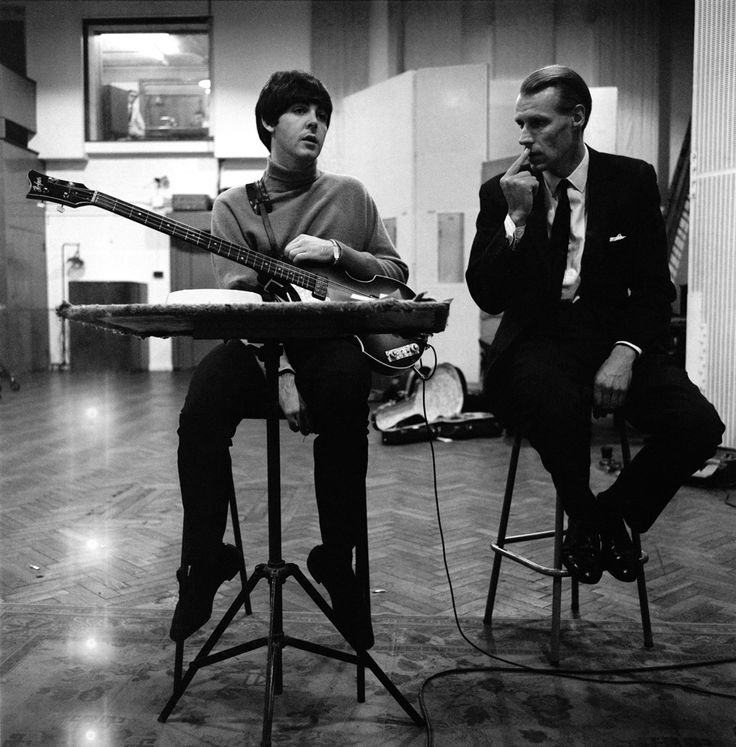 two people sitting on stools with guitars in front of them and one person holding a guitar