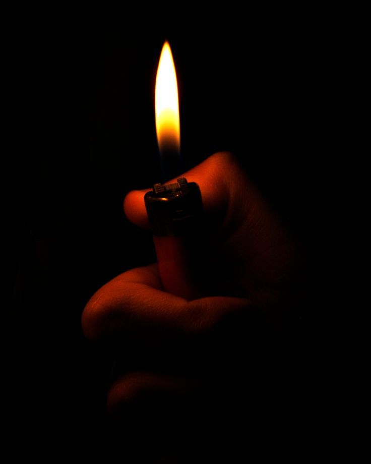 a hand holding a lighter in the dark