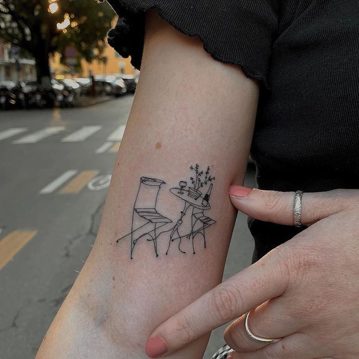 two people holding each other's hands with tattoos on their arms, one has a chair and the other is a table