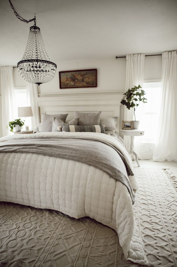 a bedroom with a chandelier hanging from the ceiling and a bed in it