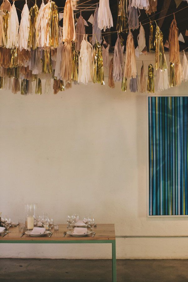 a table with place settings and tassels hanging from the ceiling in front of it