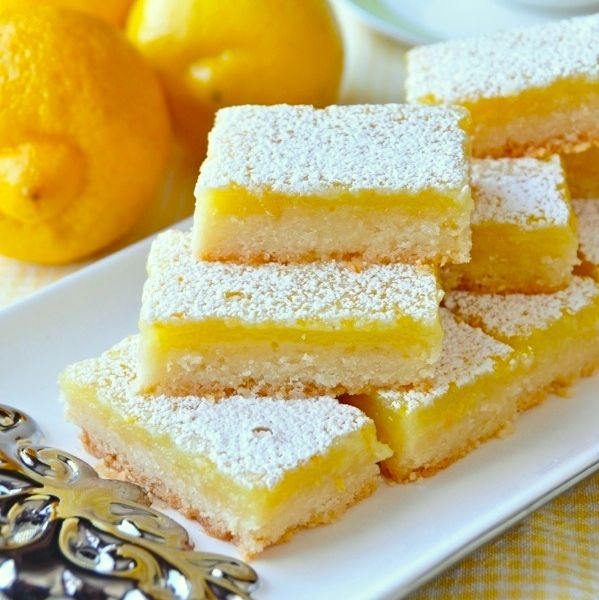 lemon bars are stacked on a white plate