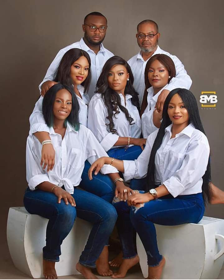 a group of people sitting on top of a white chair posing for a photo with their arms around each other