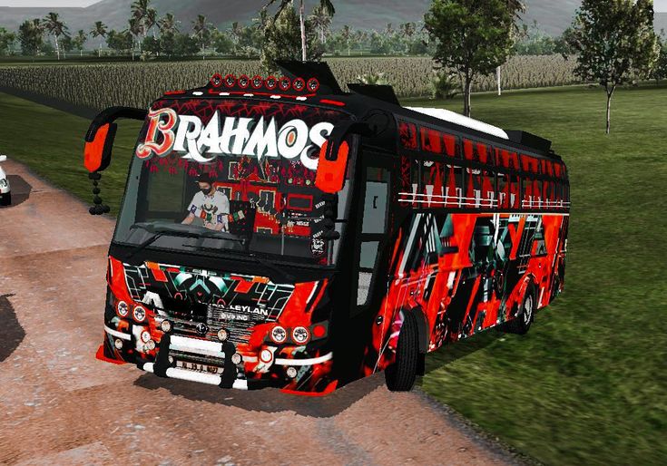 a red and black bus driving down a dirt road next to a lush green field