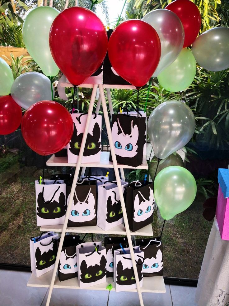 there are many balloons and bags on the stand in front of the window that is decorated with black cats