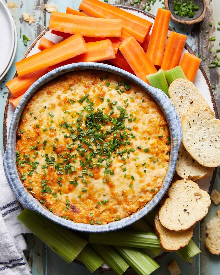 carrots, celery and crackers on a plate with dip in the middle