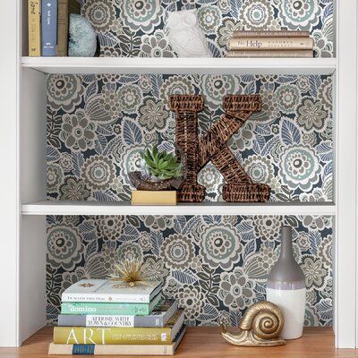 two bookshelves with decorative wallpaper on them, one is white and the other is blue