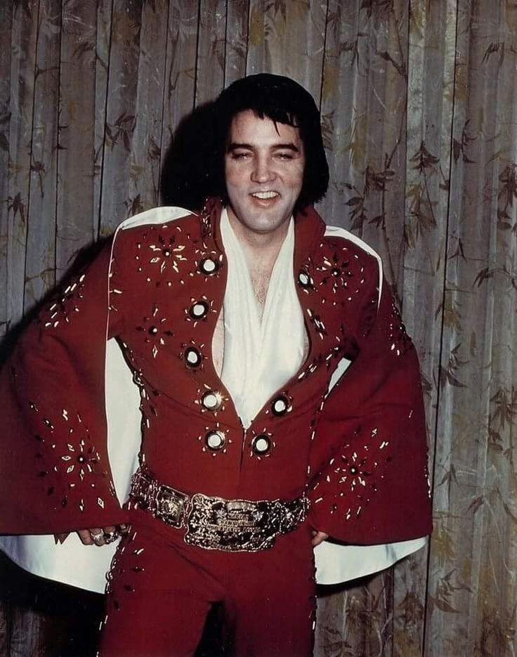 elvis presley posing for a photo in his red suit