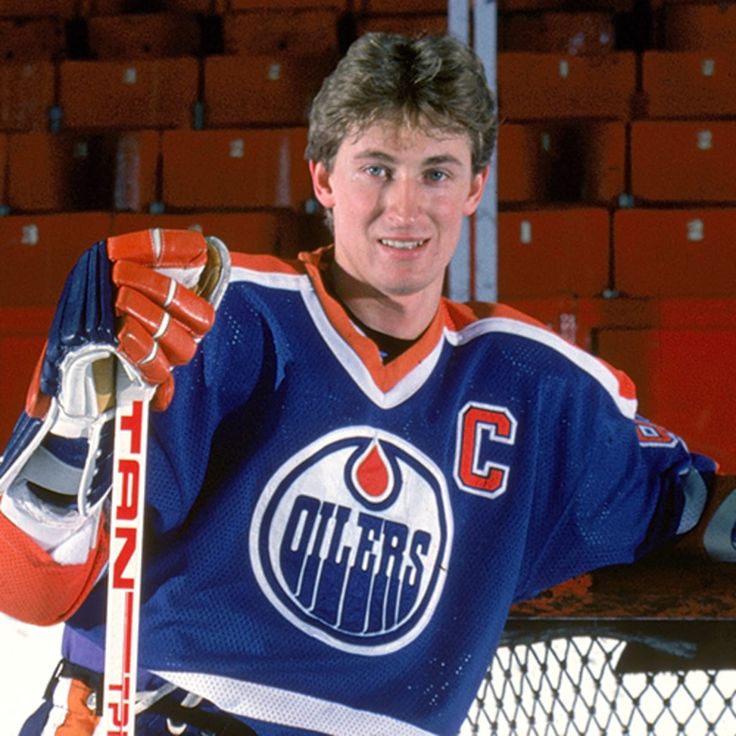 a young man holding a hockey stick in front of a goalie net