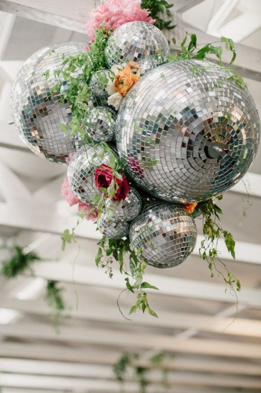 disco balls hanging from the ceiling with flowers and greenery