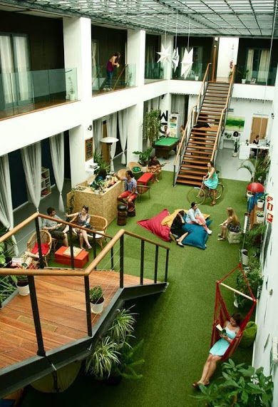 people are sitting in chairs and relaxing on the green carpeted flooring inside an apartment building