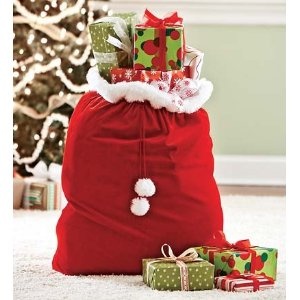 a santa sack filled with presents next to a christmas tree