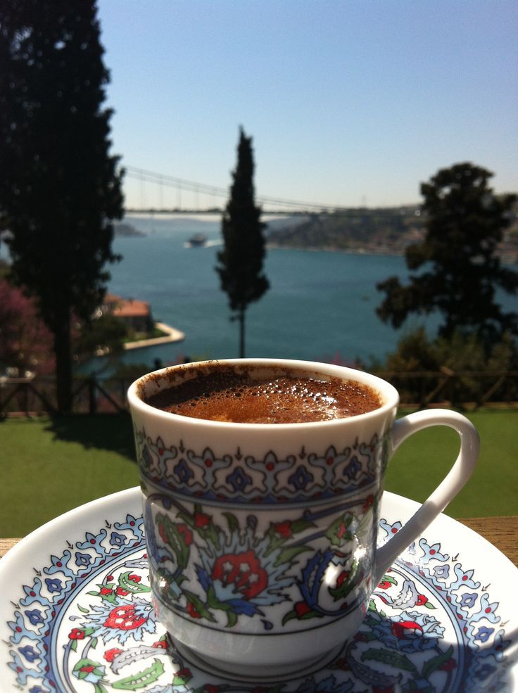 a cup of coffee sitting on top of a saucer next to a plate with an image of a bridge in the background