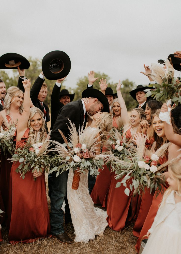 a bride and groom are surrounded by their bridal party guests with hats in the air