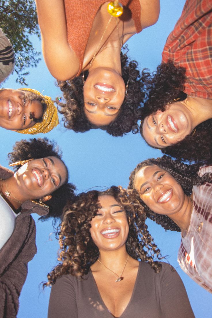 four women standing in a circle with their heads tilted to the side and smiling at the camera