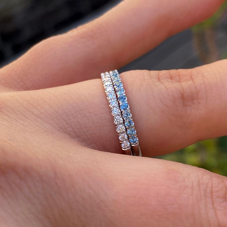 a person's hand holding a ring with three rows of diamonds on top of it