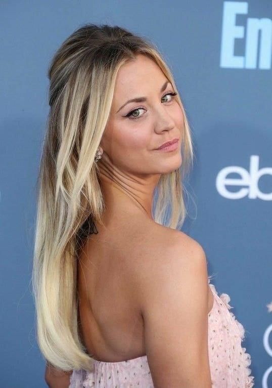 a woman with long blonde hair wearing a pink dress and looking off to the side