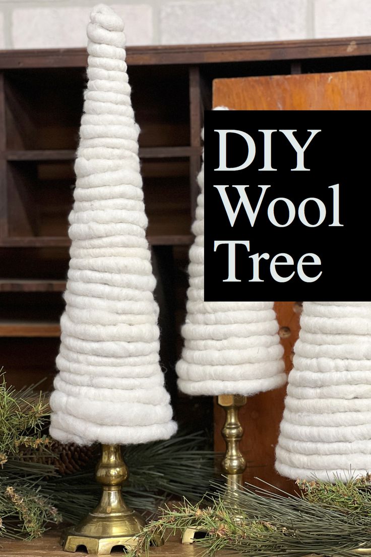 two white christmas trees sitting next to each other on top of a wooden table with a sign that says diy wool tree