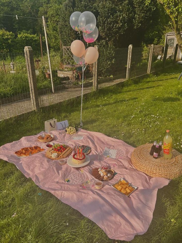 a picnic with balloons and food on the grass