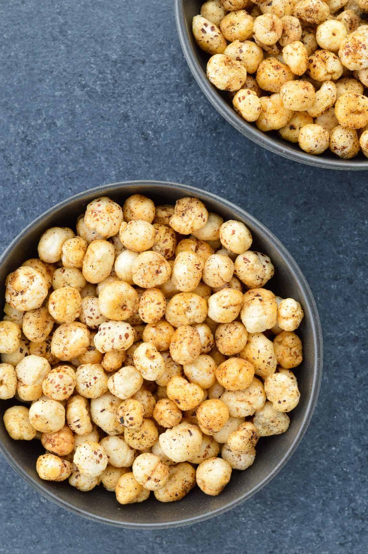 two bowls filled with chickpeas on top of a blue counter next to each other