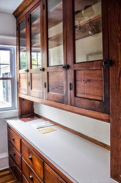 an empty kitchen with wooden cabinets and white counter tops in front of a large window