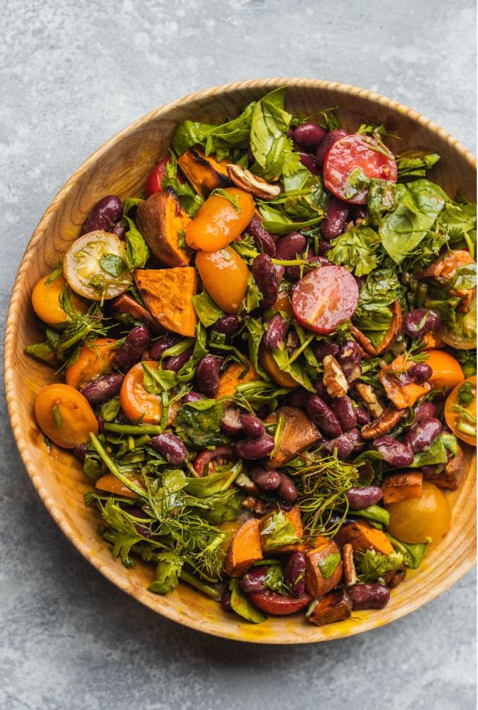 a wooden bowl filled with lots of veggies and other food on top of a table