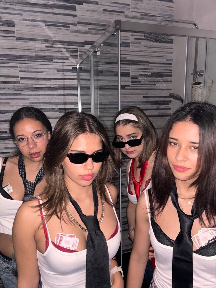 four women wearing blindfolds are posing for a photo in front of a mirror