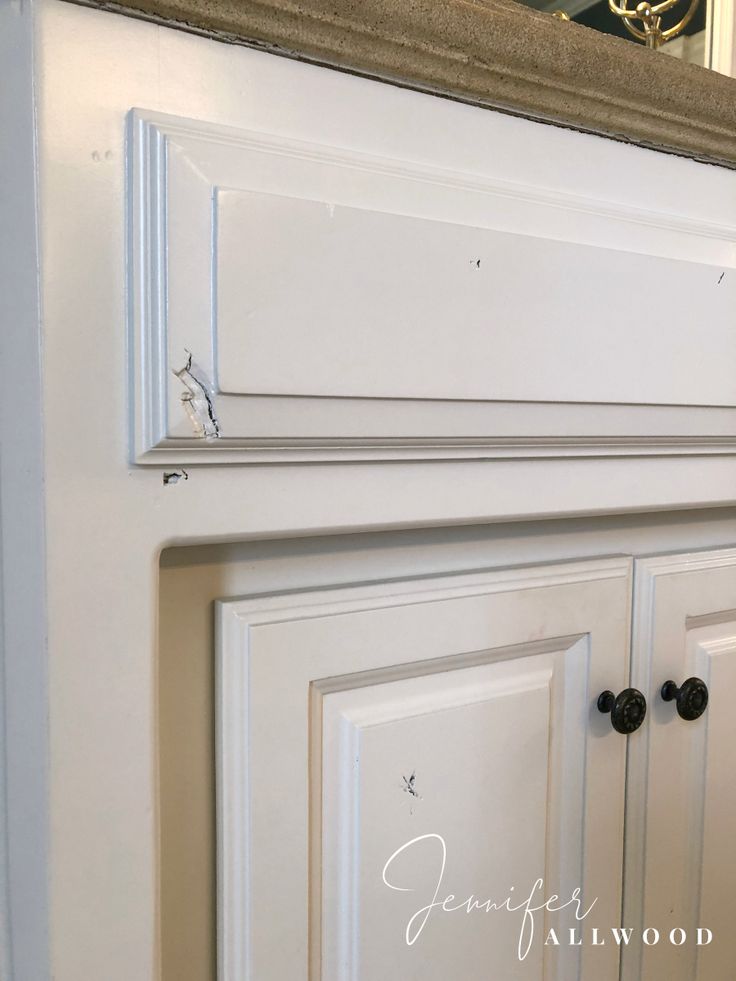 a white cabinet with two knobs and a mirror above it that says anniewood