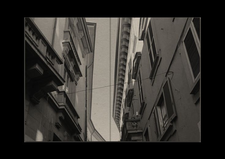 two tall buildings with windows and balconies on the side of each building in black and white