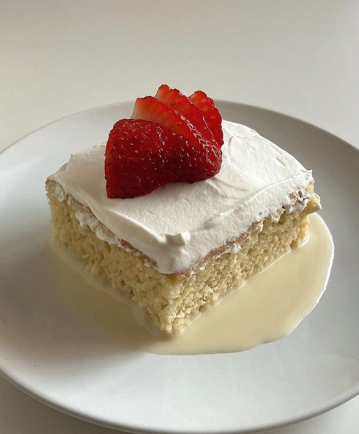 a piece of cake with whipped cream and strawberries on top sits on a plate