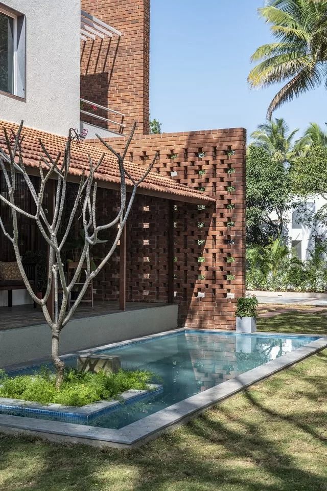 an outdoor swimming pool in front of a brick building with trees and grass around it