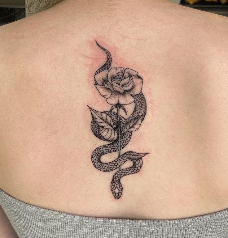 a woman with a snake and rose tattoo on her back