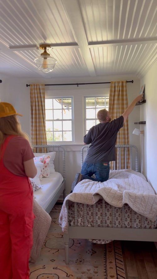 two people standing in a bedroom next to a bed